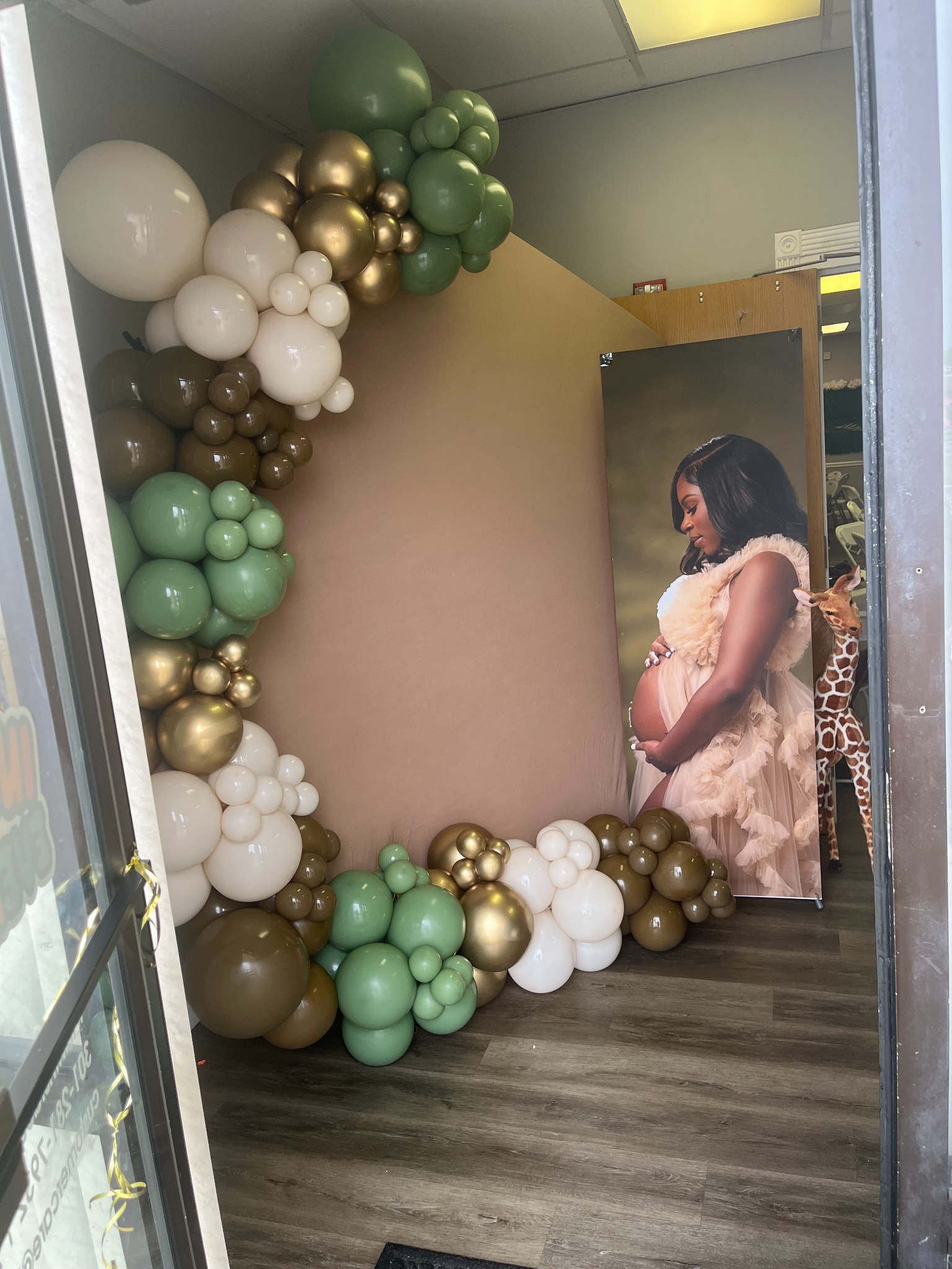 Green, cream, and gold balloon display beside a maternity portrait